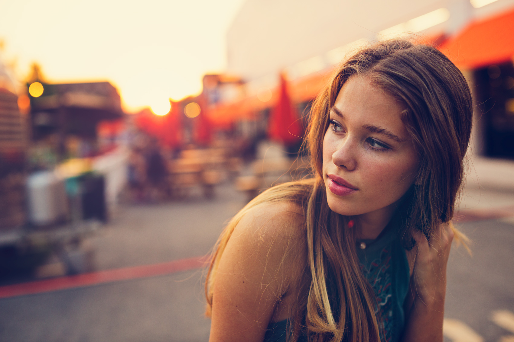 A teenage girl sits outside of Union Market in Washington, DC during a summer sunset.
