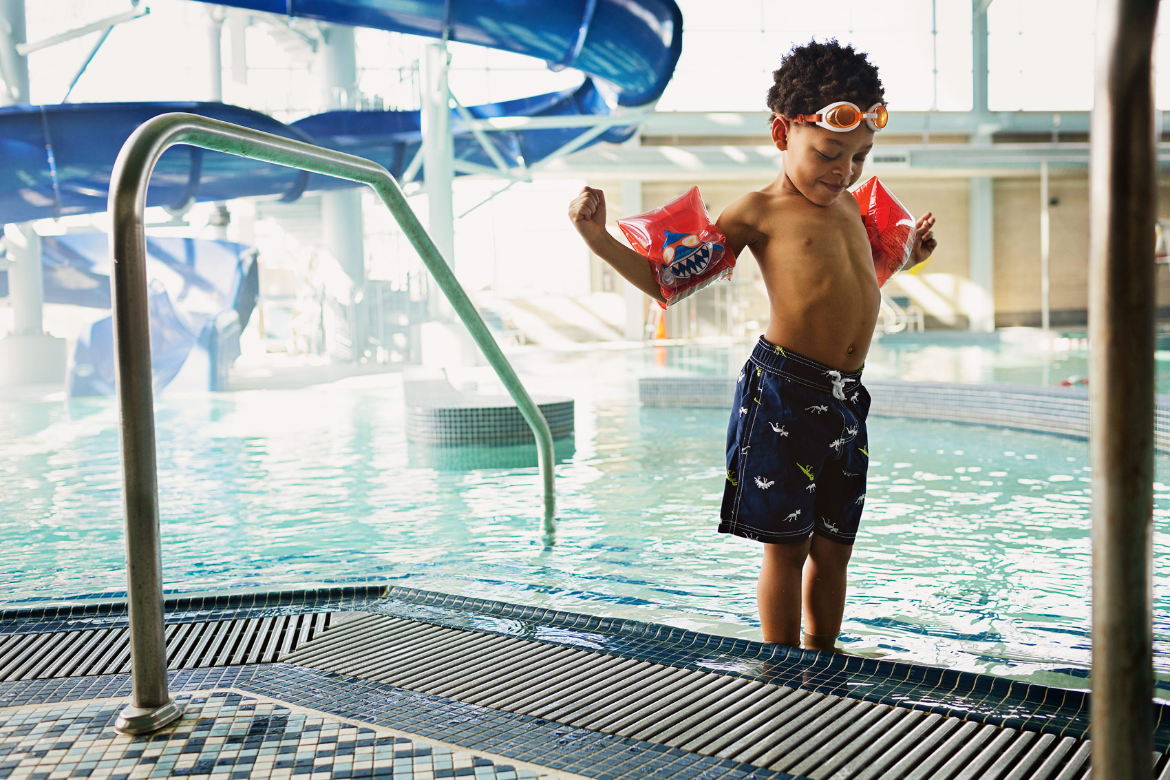 A young boy flexes his muscles with floaties on at a Washington, DC pool.