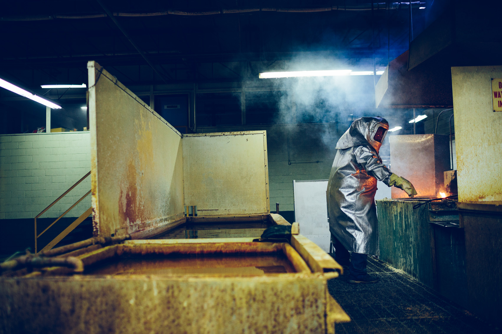 A worker dips an aluminum chair in a bath during production at Emeco