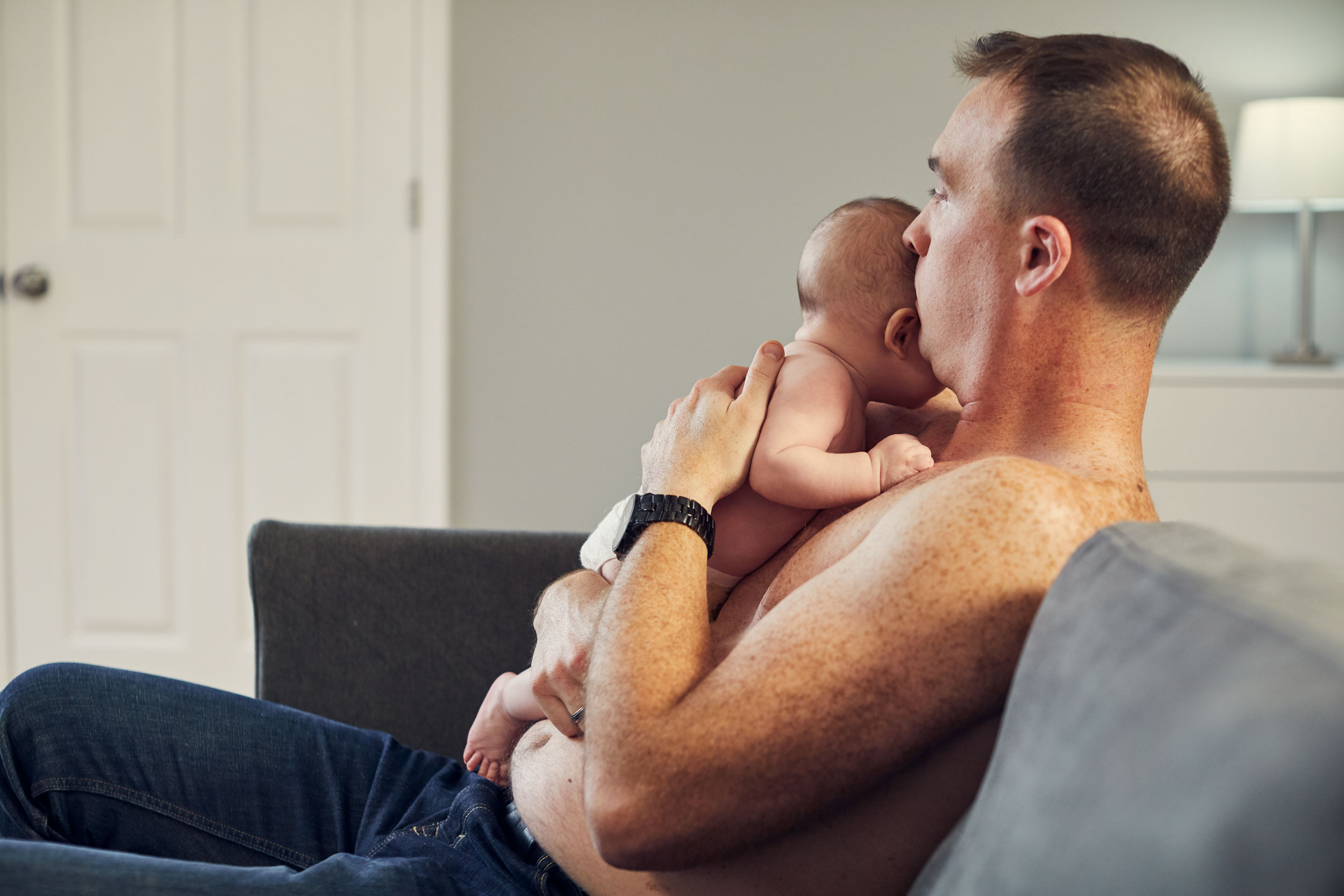 father holding baby for skin to skin on couch, washington dc commercial photography