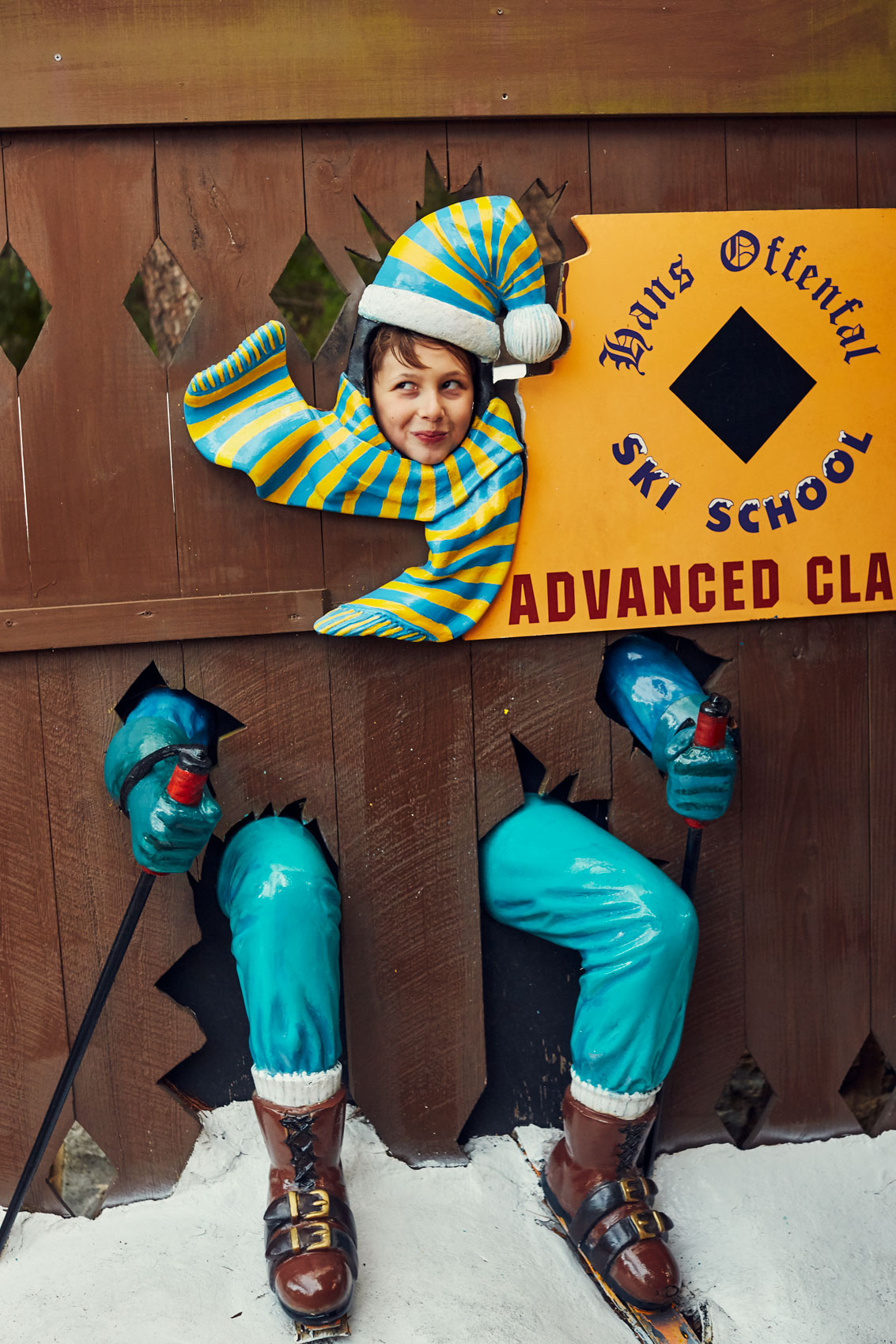 A tween boy poses for a photo at an amusement park photo cutout.
