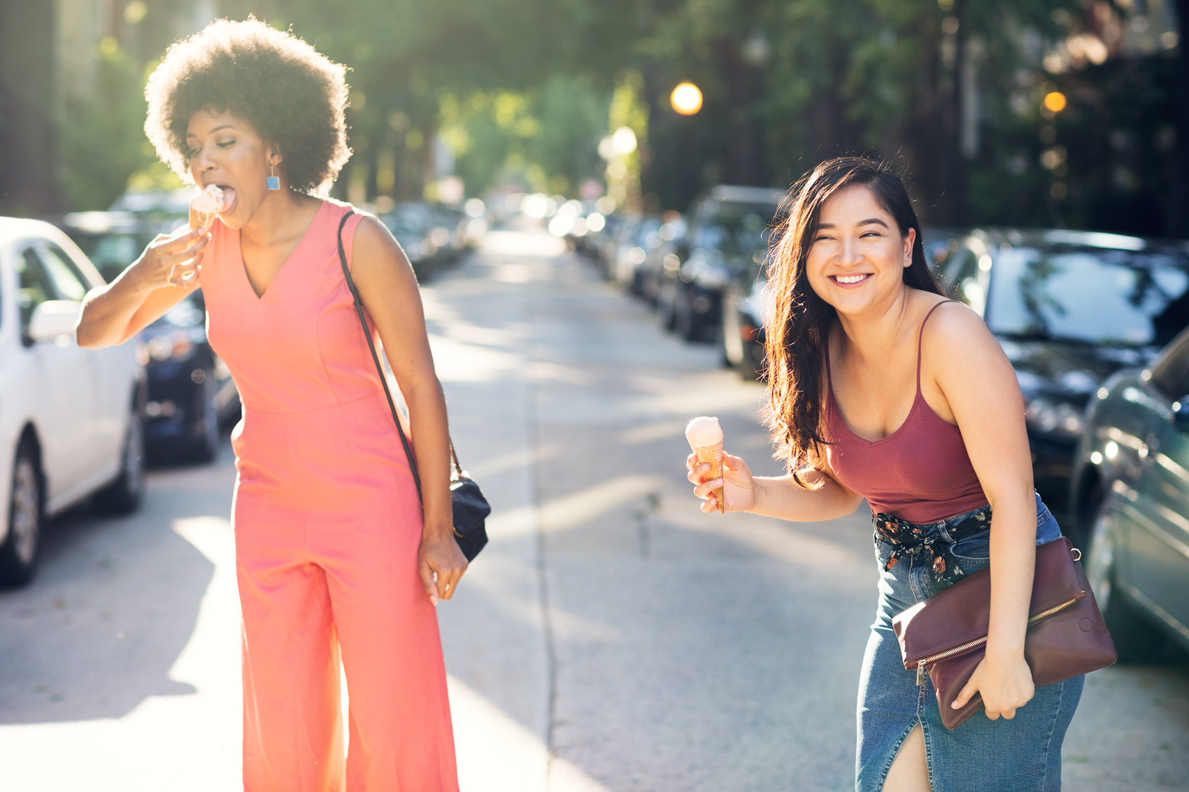 Two young women laugh as they eat melting ice cream cones in the middle of a Washington, DC street.