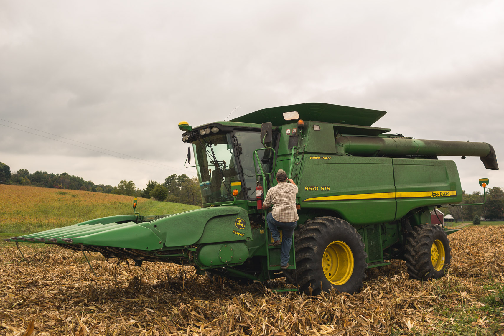 A farmer climbs down a John Deere harvester while working in a corn field in Maryland.