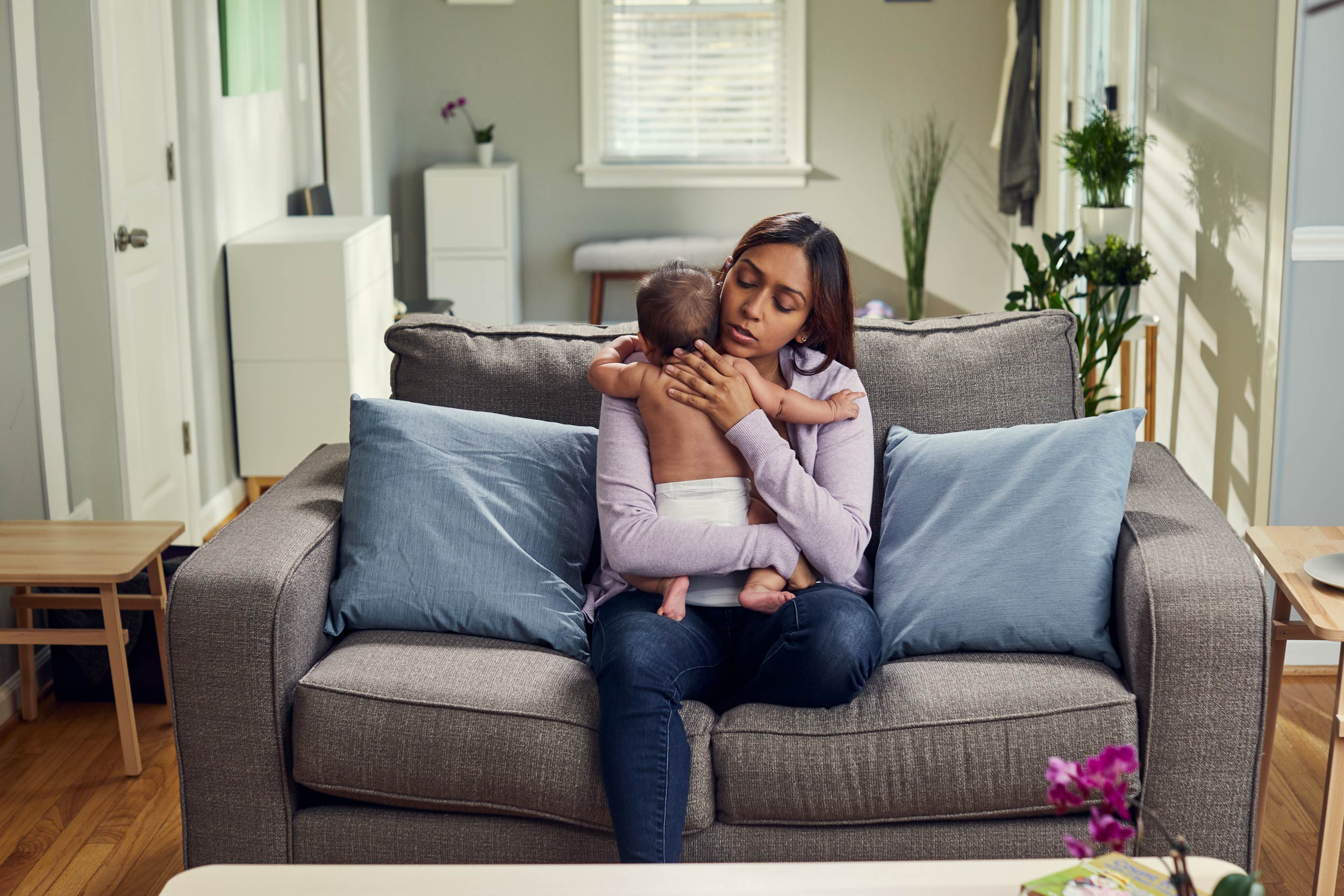 mom comforting baby on couch in living room, washington dc commercial photography
