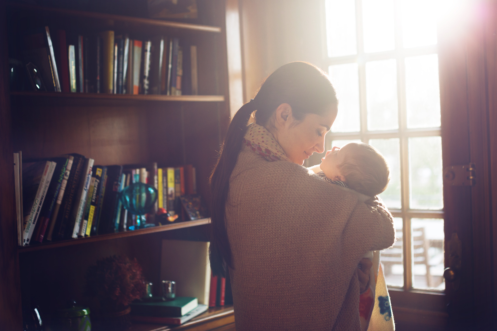 mother holds her baby in front of books for washington dc commercial photography