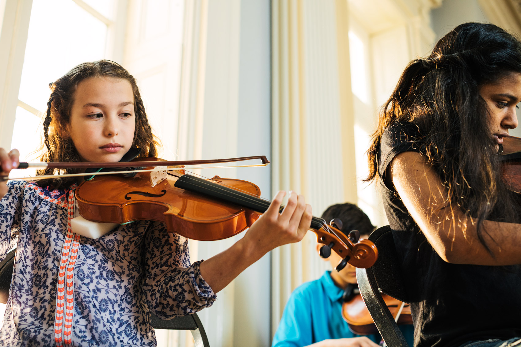 adolescent kids playing violins inside by window, washington dc commercial photography