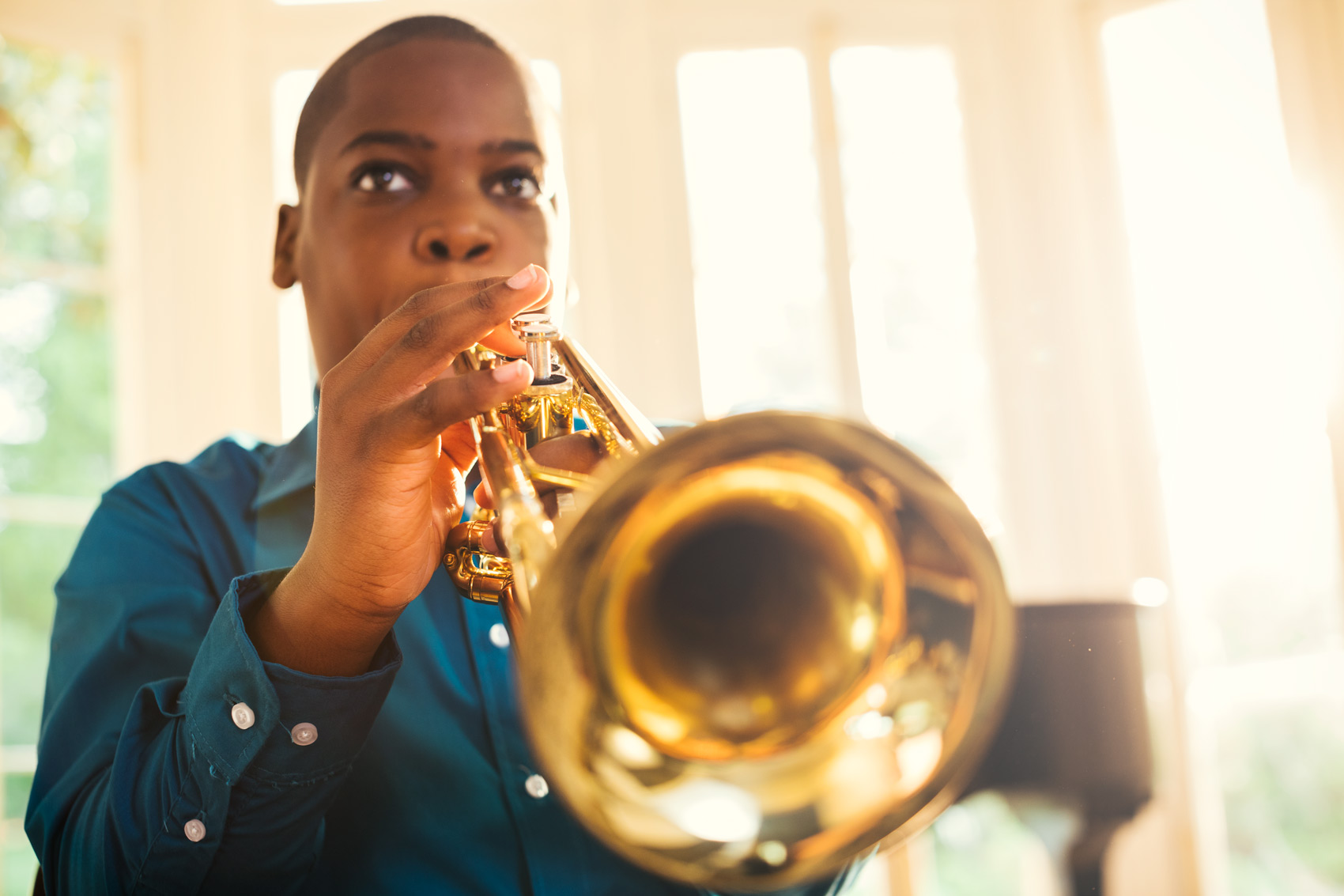 adolescent boy playing trumpet by window, washington dc commercial photography
