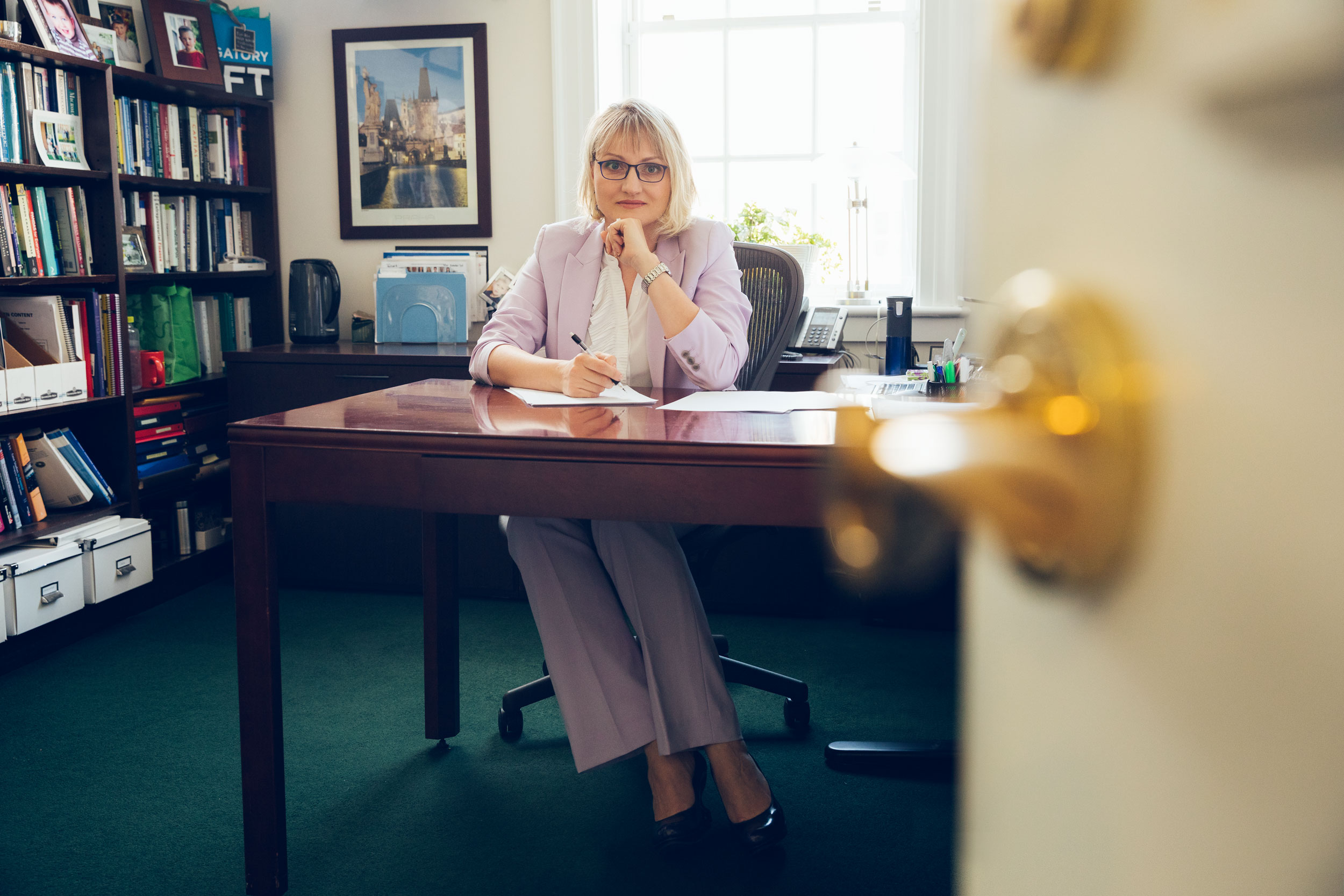 A professor at University of Virginia Darden School of Business poses for a portrait at her office desk.