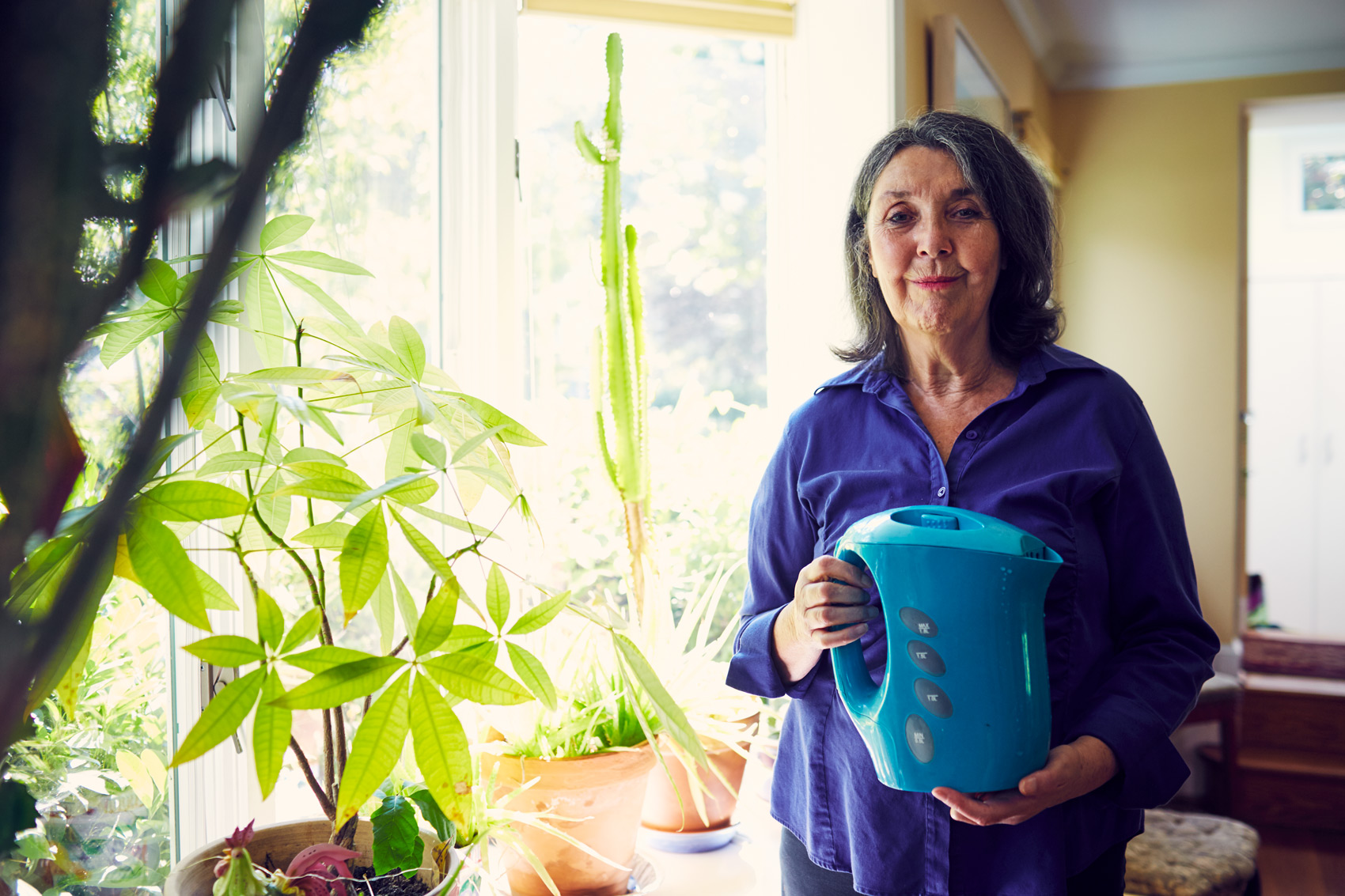 mature woman in blue shirt holding watering can, washington dc commercial photography