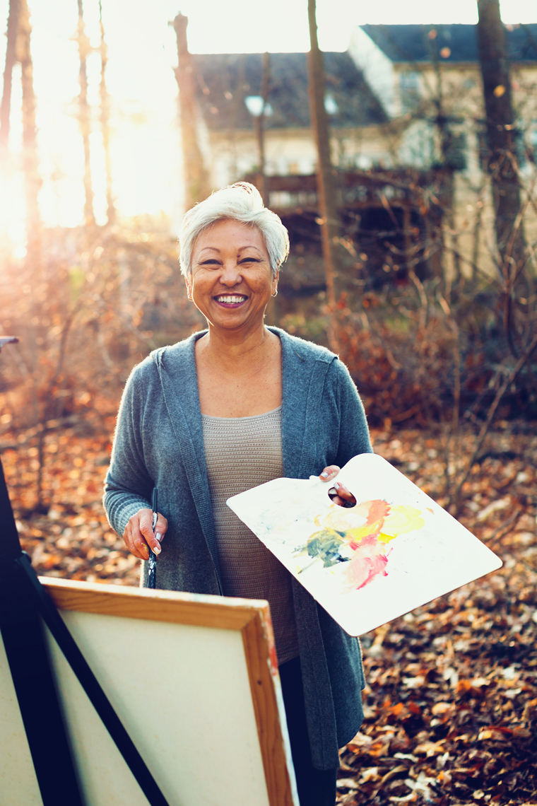 gray haired woman painting in trees, washington dc commercial photography