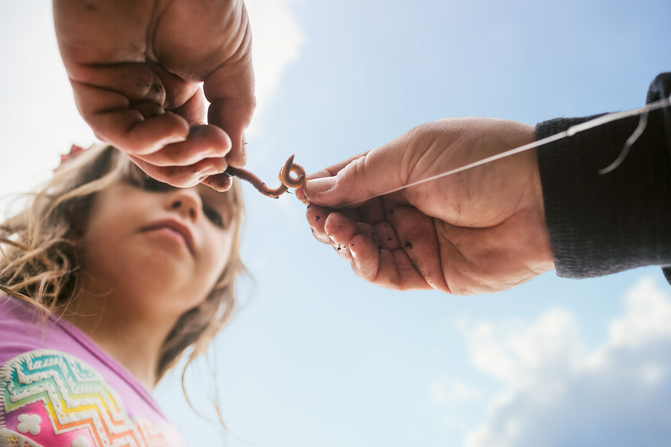 hands hooking worm under sky with girl, washington dc commercial photography