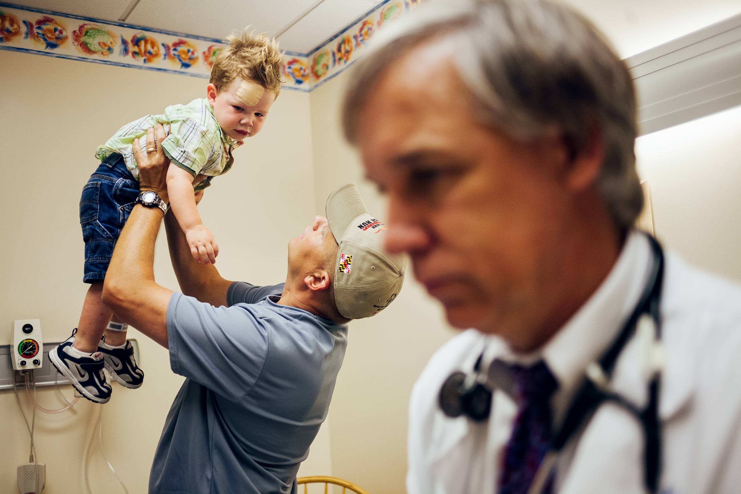 father raising boy in air at pediatrician, washington dc photojournalism