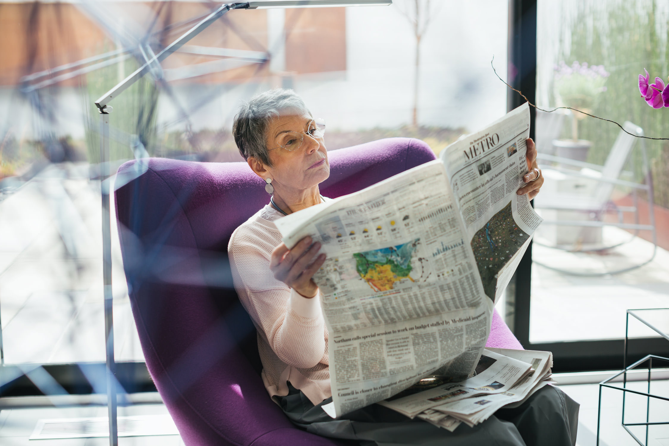 mature woman with gray hair reading newspaper in purple chair, washington dc commercial photography